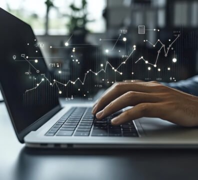 group of business professionals working together in an office, using laptops and tablets to analyze financial data with charts on screen